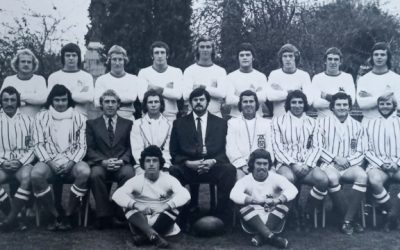 Rhodes University 1st Team Rugby (1974). Donovan Neale-May is seated on the left in the front row, with coach Neilen Locke appearing third from the left in the same row. Next to Locke (in white blazer) sits Ally Weakley, who was the team Captain at the time.
